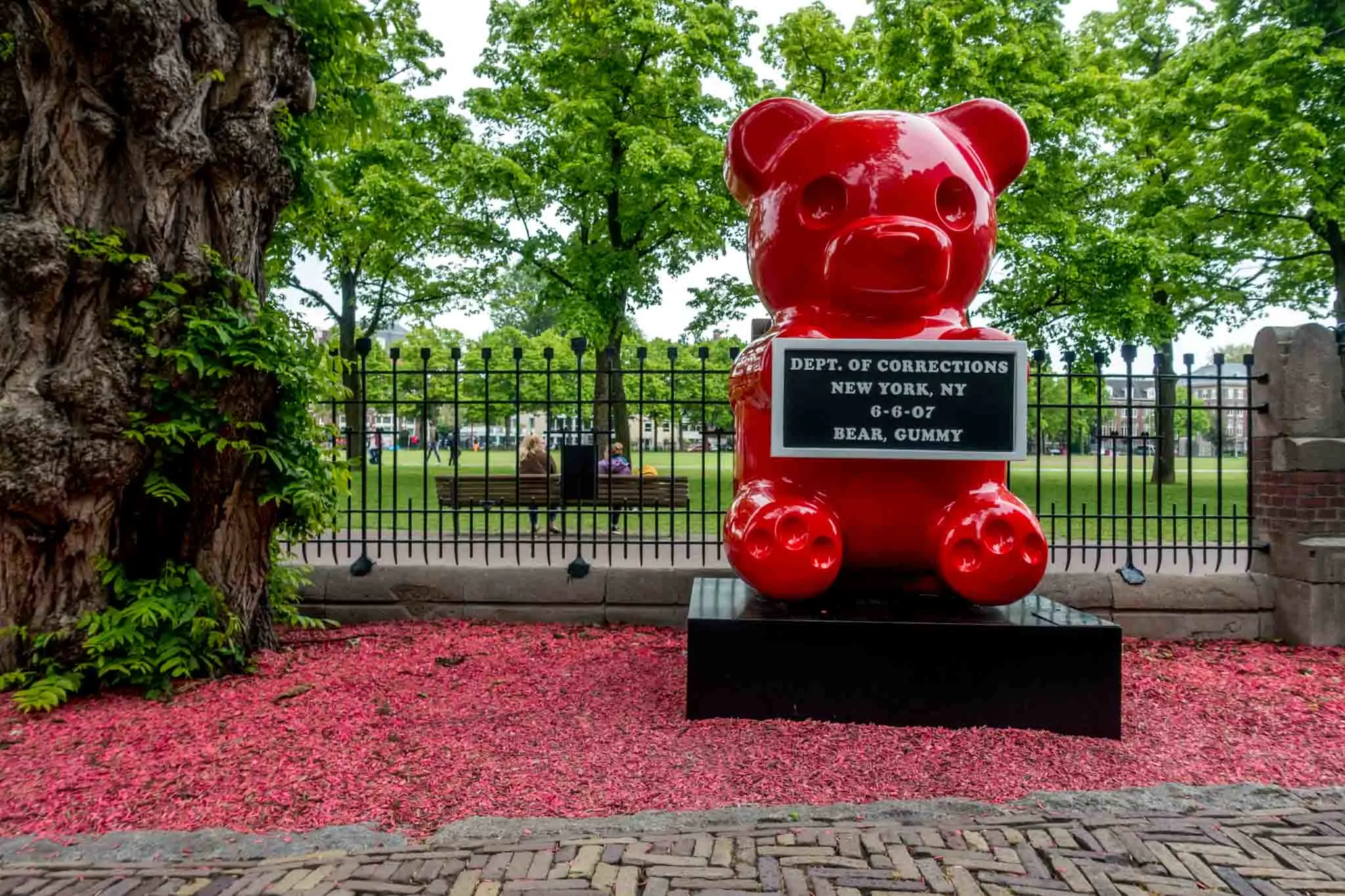 Red gummy bear statue holding a mug shot plaque 