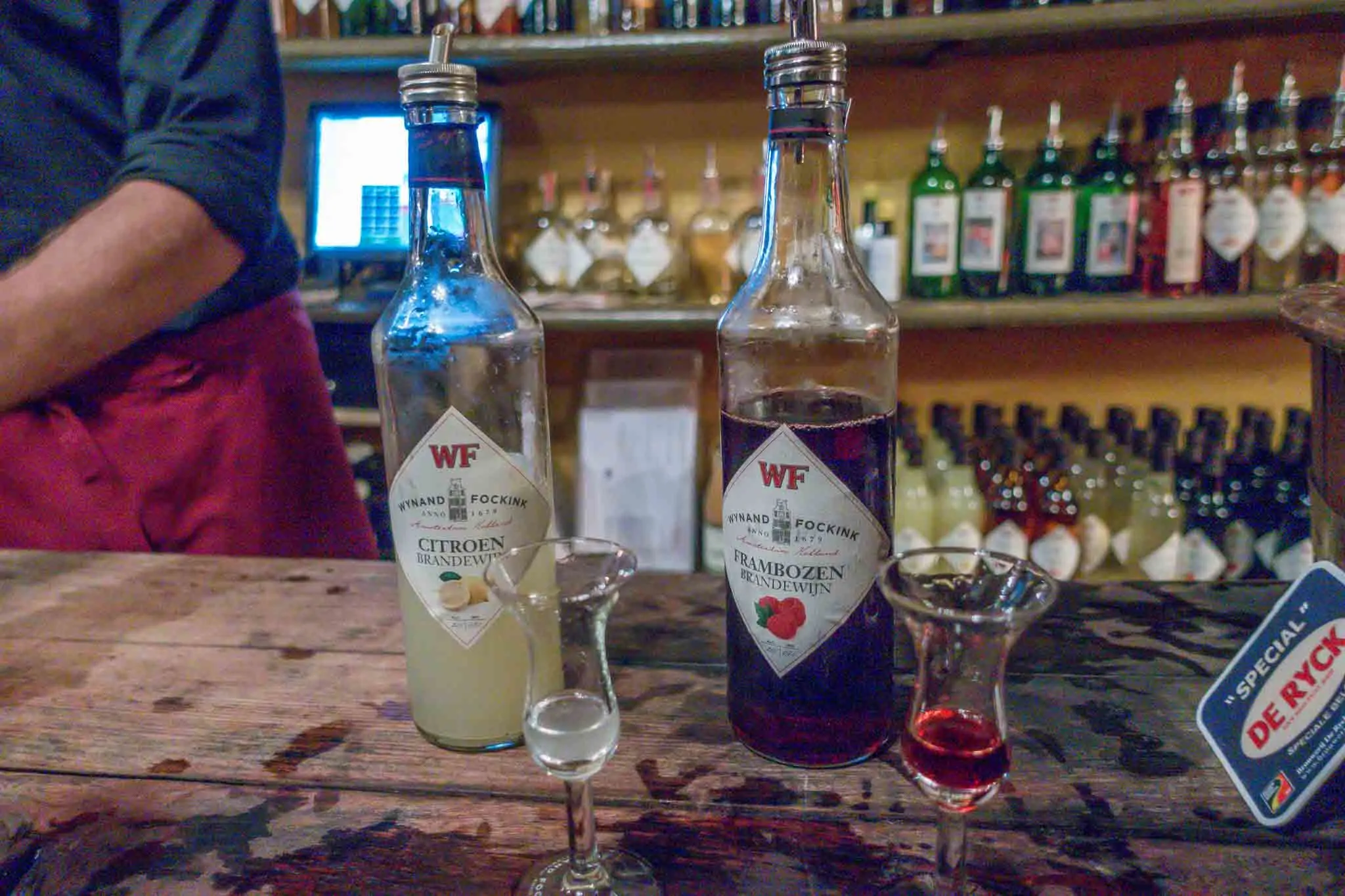 Bottles and glasses of fruit brandy on a bar.