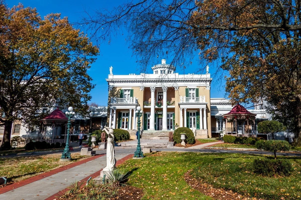 Exterior of a yellow and white mansion with columns.