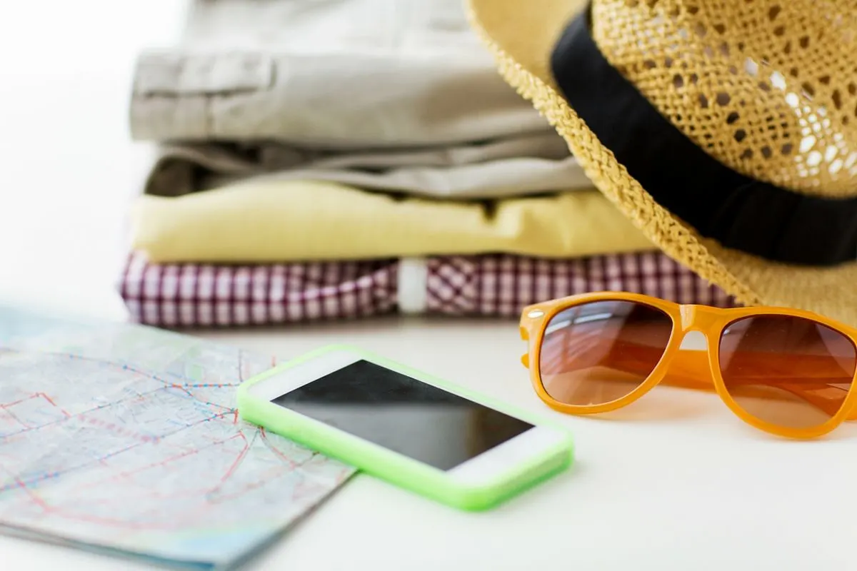 Phone, map, sunglasses, and clothes ready for a trip