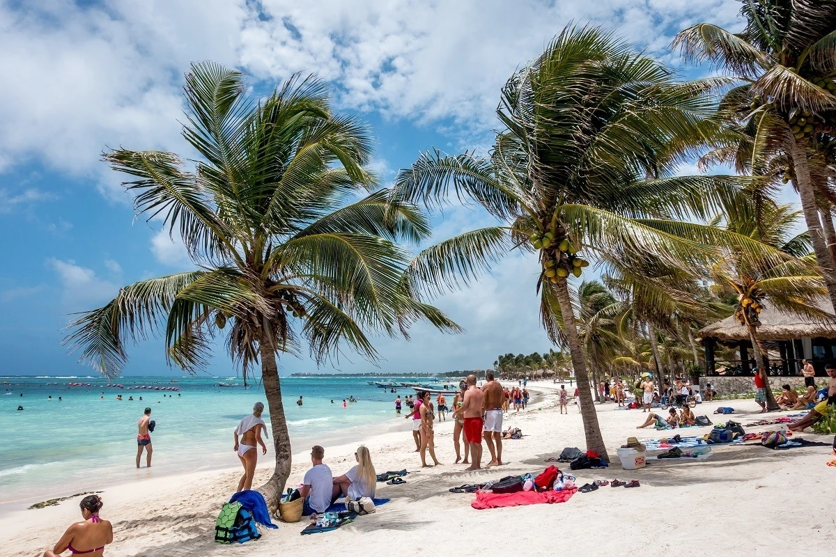 People under palm trees on Akumal beach Mexico