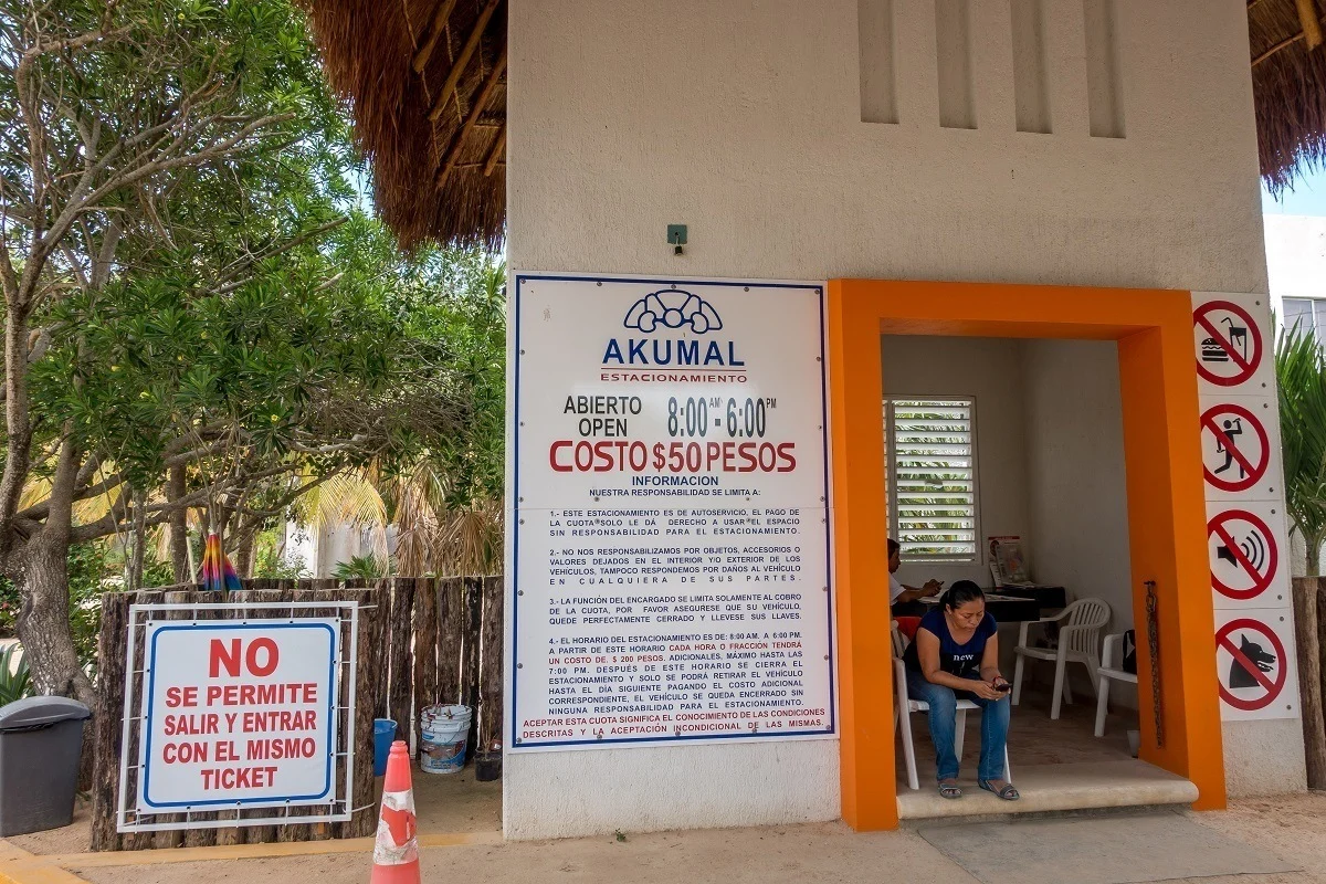 Parking attendant and sign with rates and times for parking 