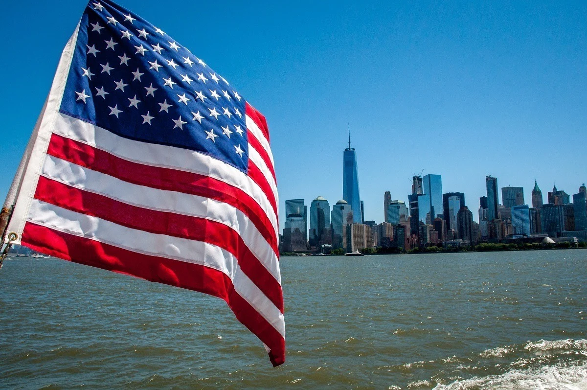 An American flag flying with the New York skyline in the background
