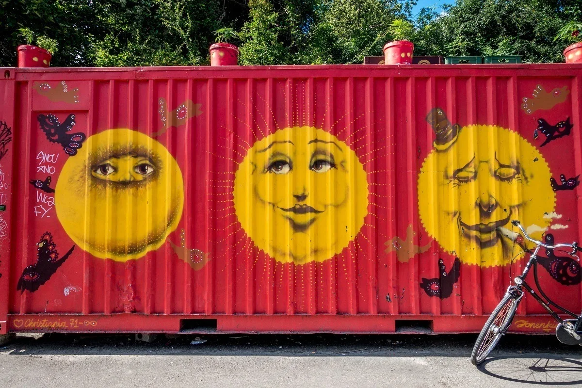 Container painted red with three large yellow faces