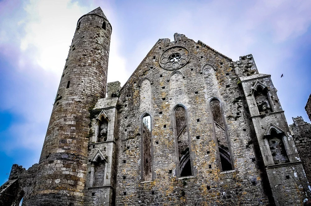 Stone round tower and facade of an ancient cathedral 