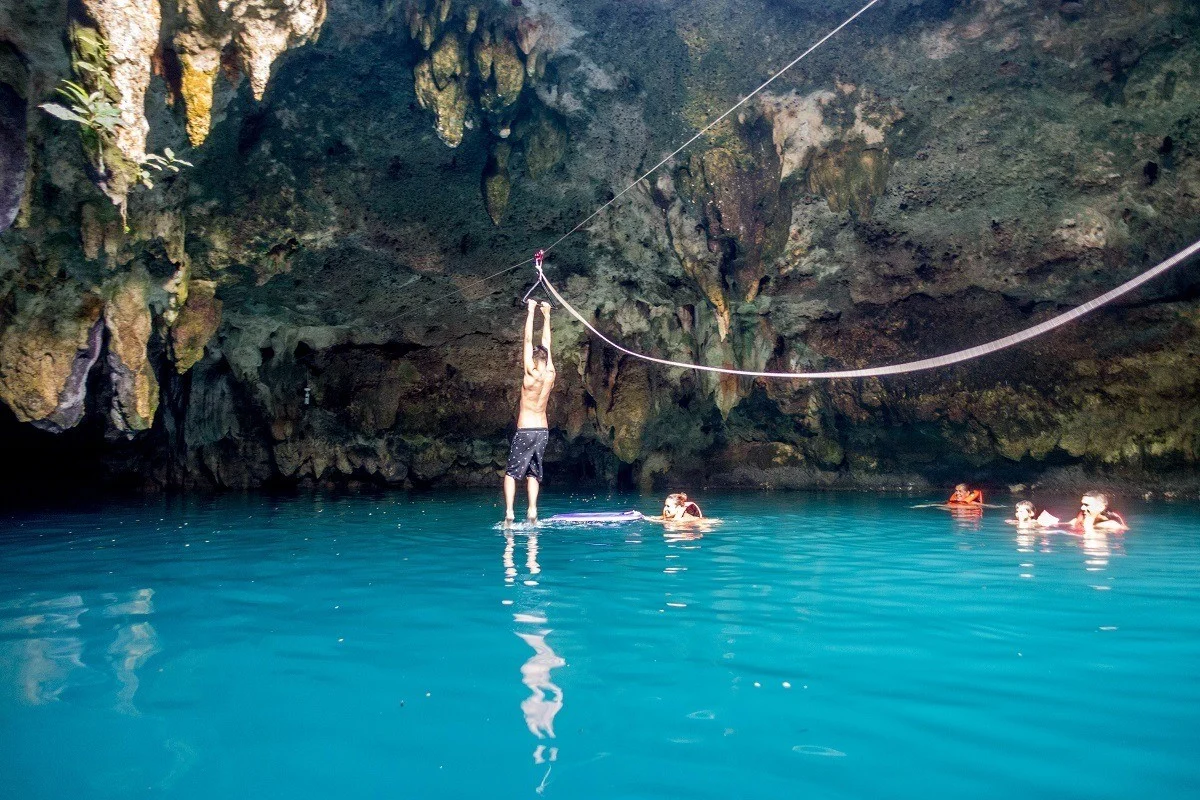 A zip line in the Cenote la Noria with people swimming