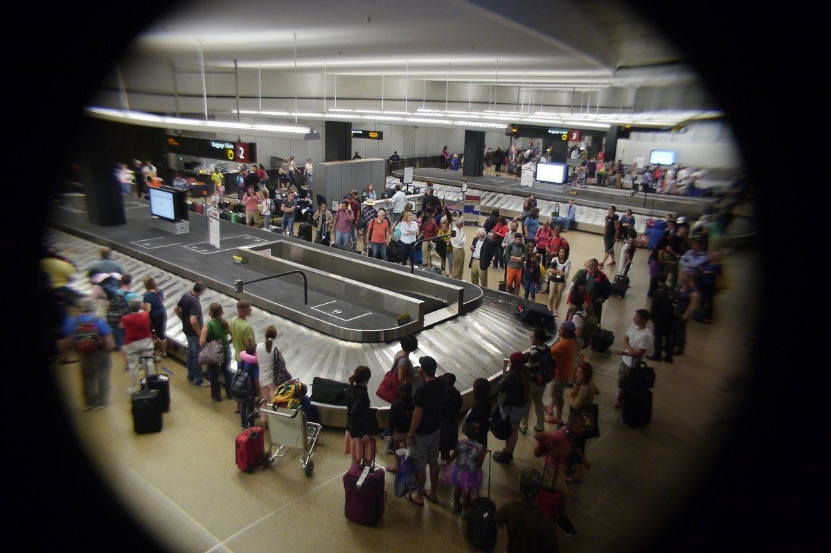 People waiting around a baggage carousel wondering if their luggage is lost