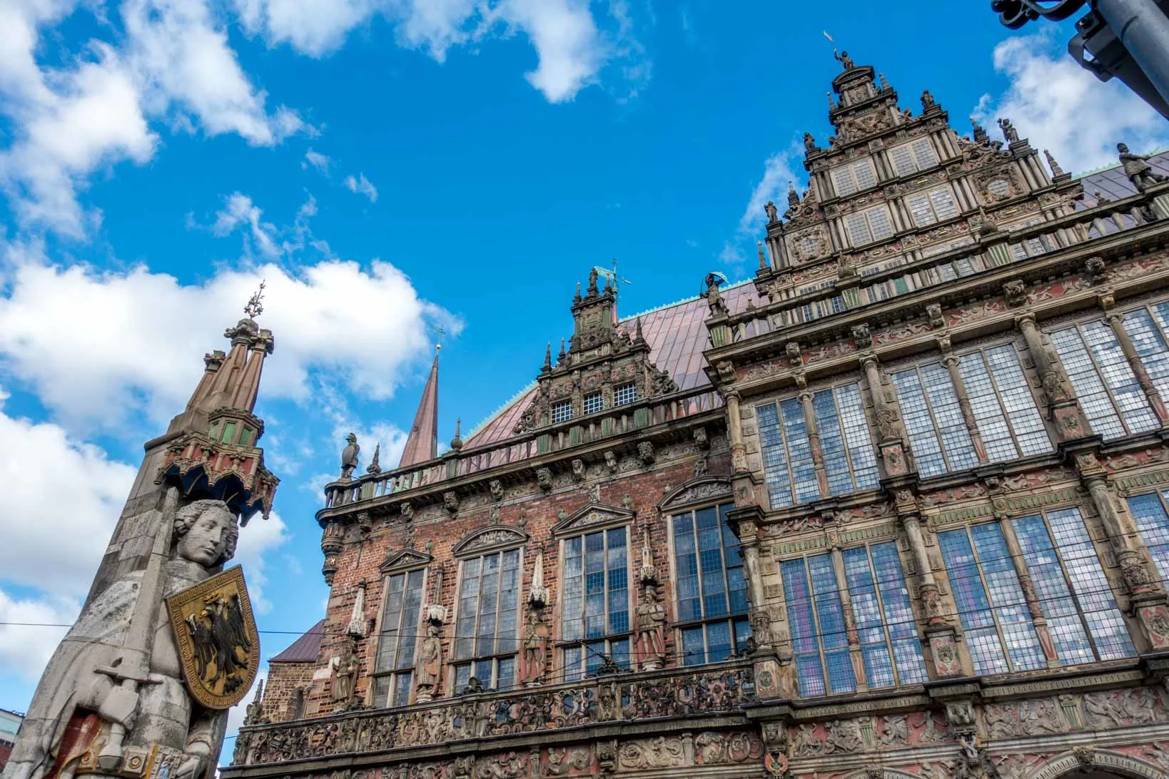 Window-filled exterior of Bremen Town Hall and statue of a man, Bremen Roland