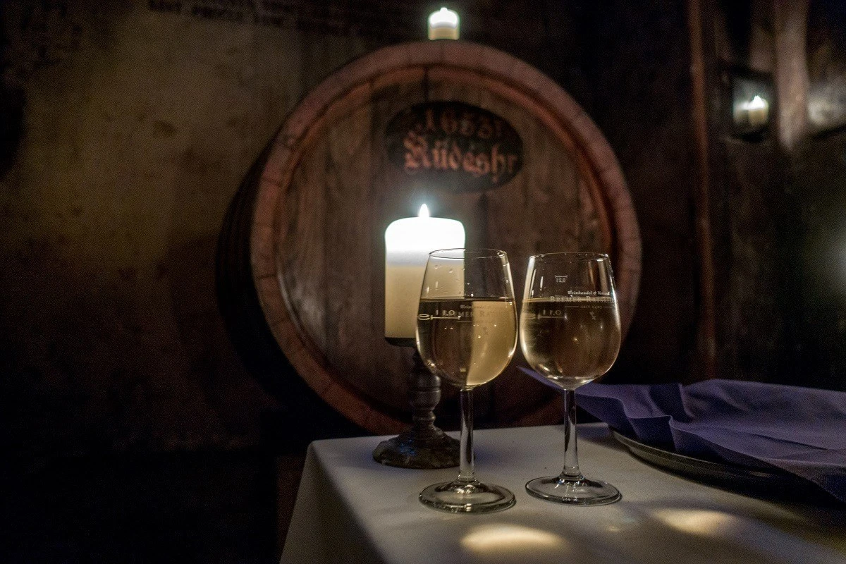 Two wine glasses lit by a candle by a wine barrel