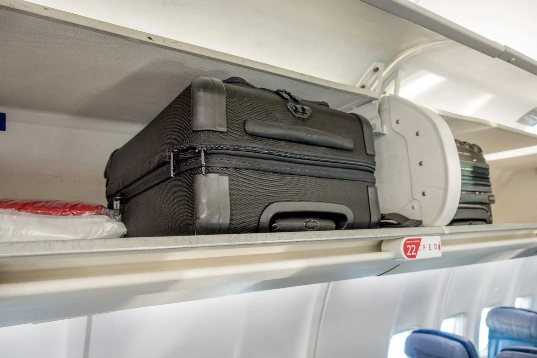 Two carry-on suitcases in an airline overhead bin