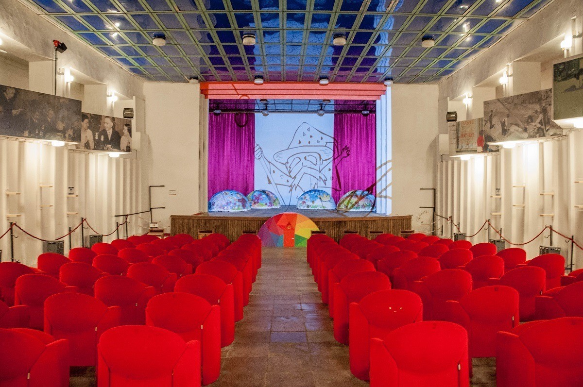Room with a stage and red chairs