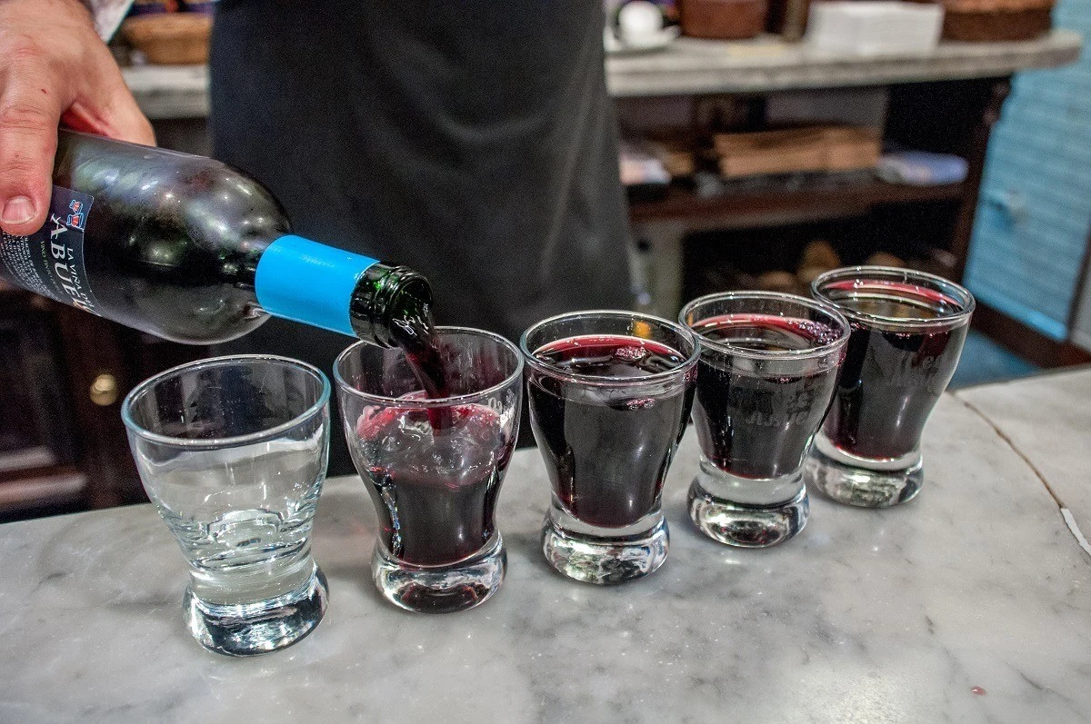 Person pouring red wine into glasses
