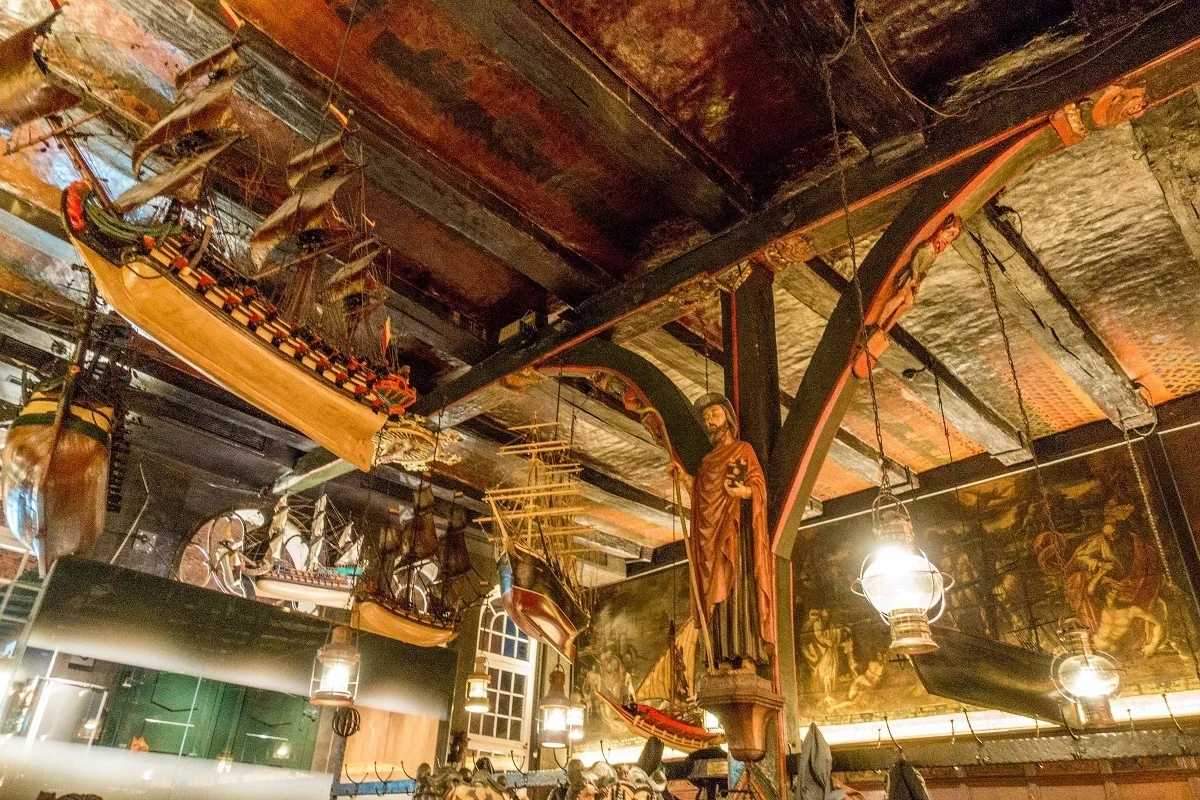 Ceiling with nautical themed items hanging from wooden beams 