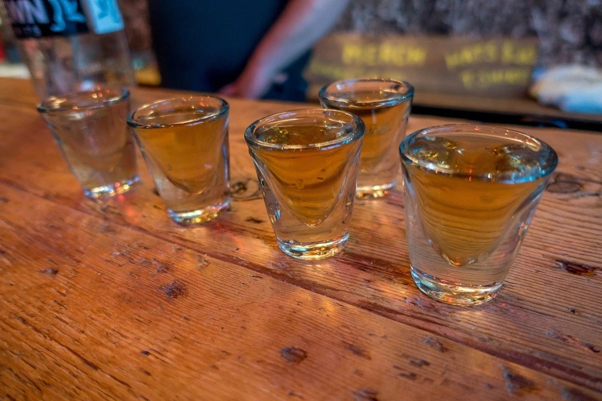 Five shot glasses full of spirits on a wooden bar 