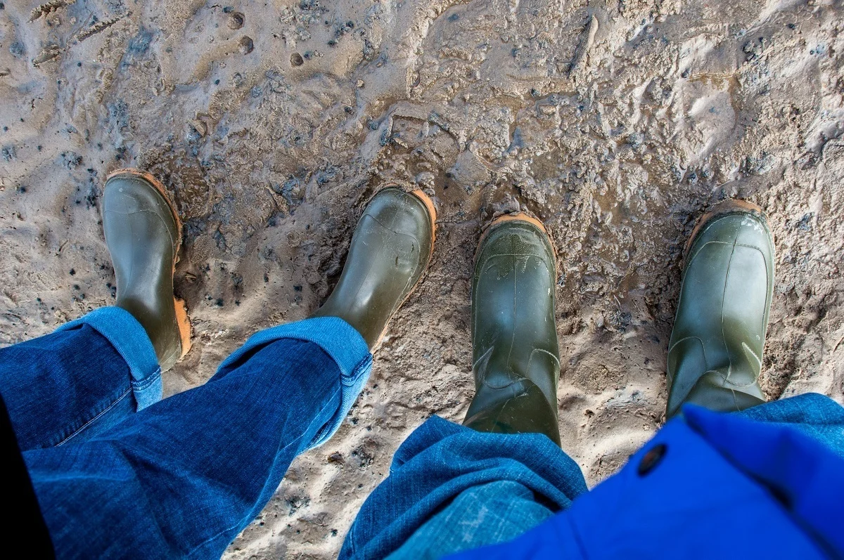 Two people in mud boots standing in the mud on the salt flats