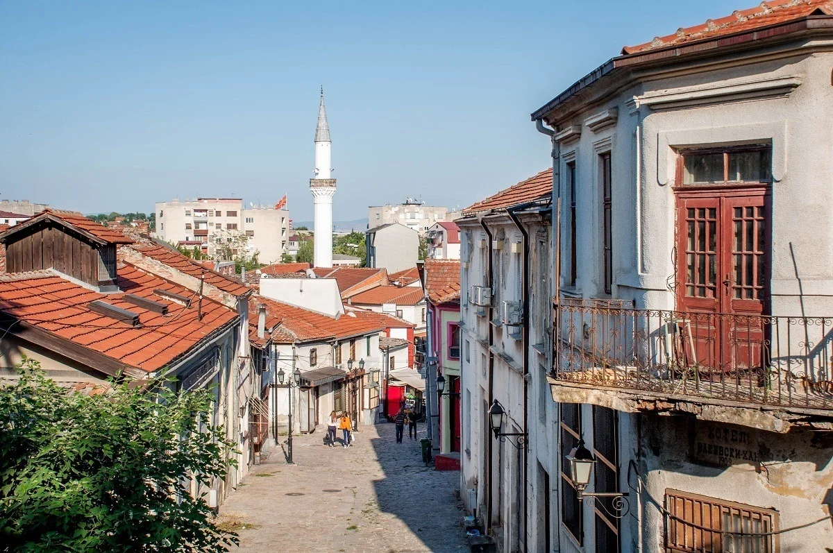 Cobblestone street lined with stores and a minaret in the distance