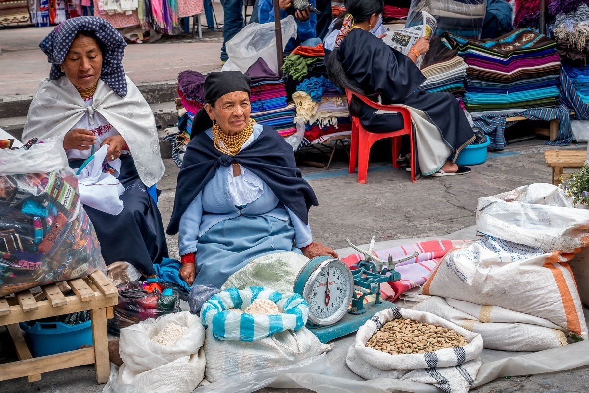 Women in traditional dress selling their goods in Otavalo, Ecuador