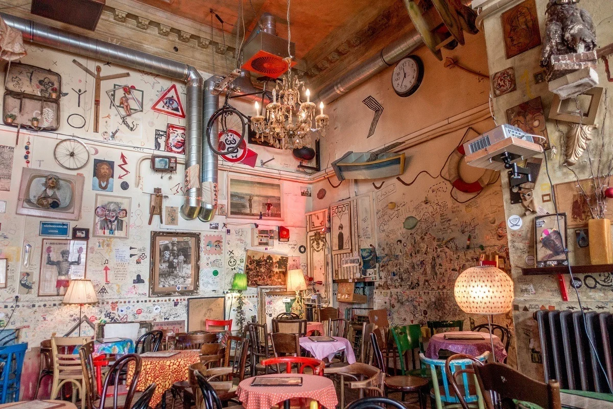 Tables in a room with graffiti and photos on the walls. 