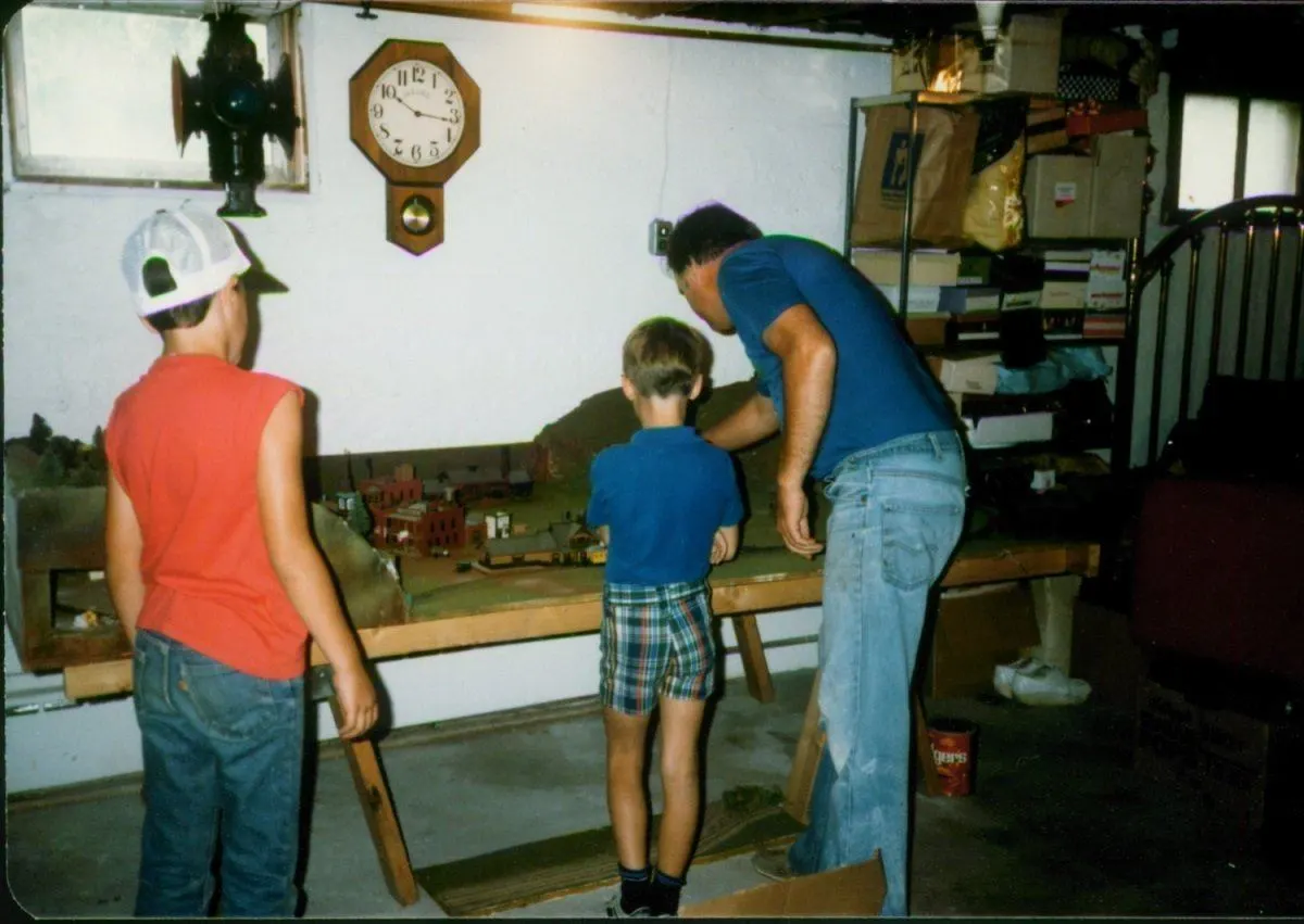 Lance working on train set with his dad and friend in 1984
