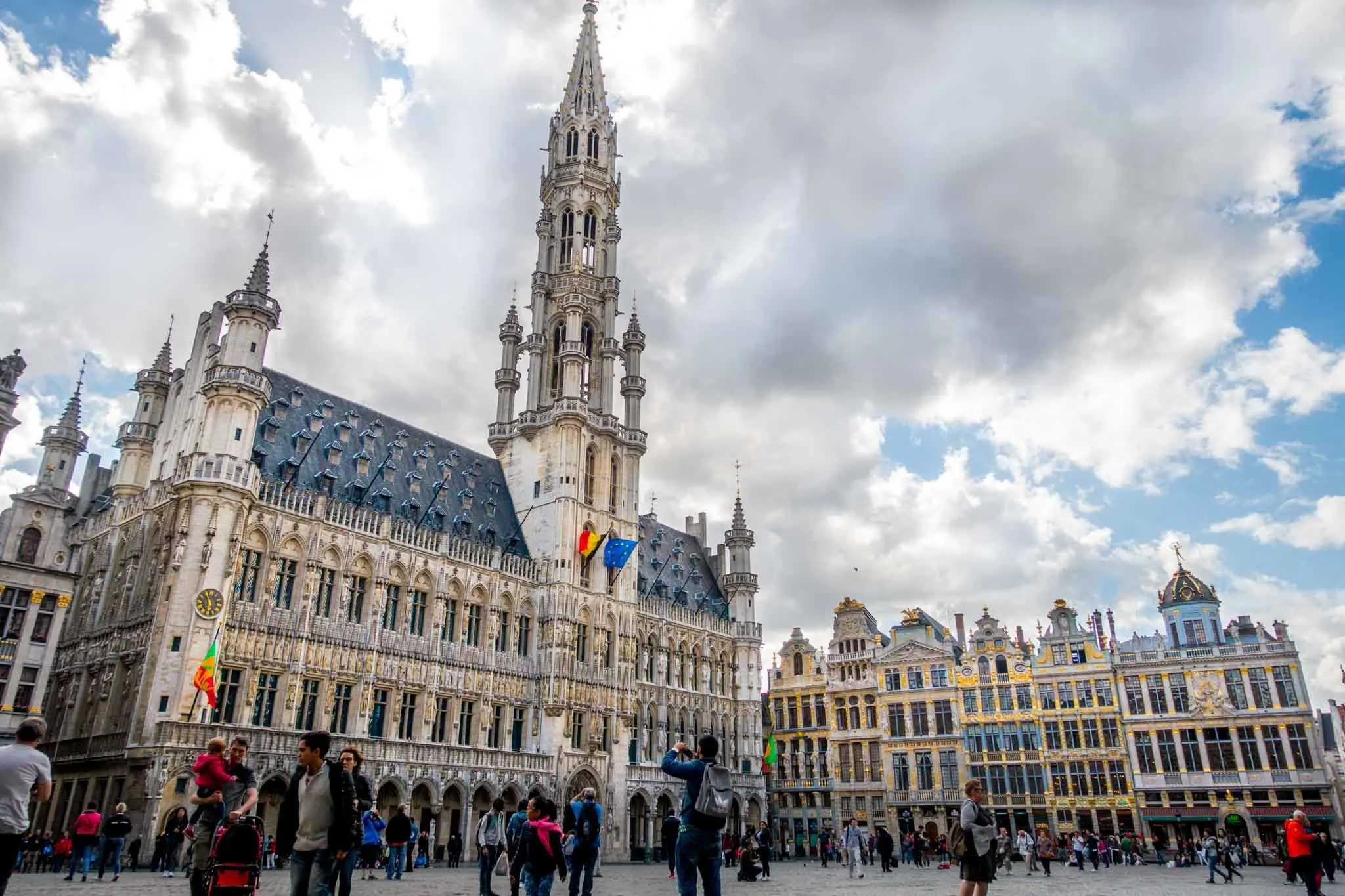 People looking at ornate buildings around a city square.