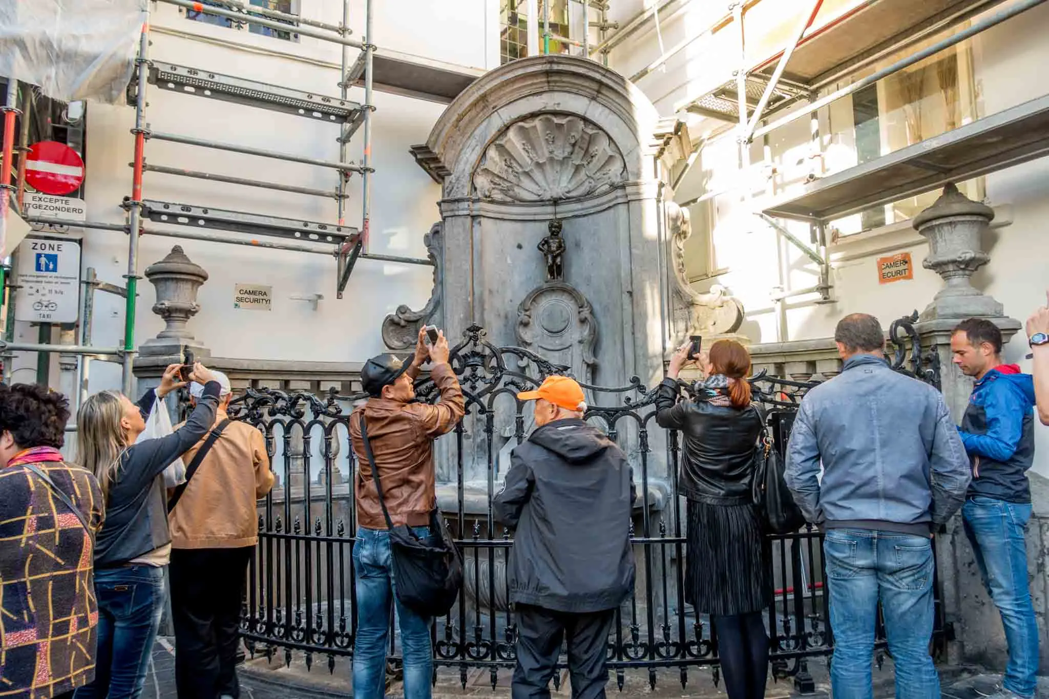 Tourists photographing a statue of a little boy peeing.