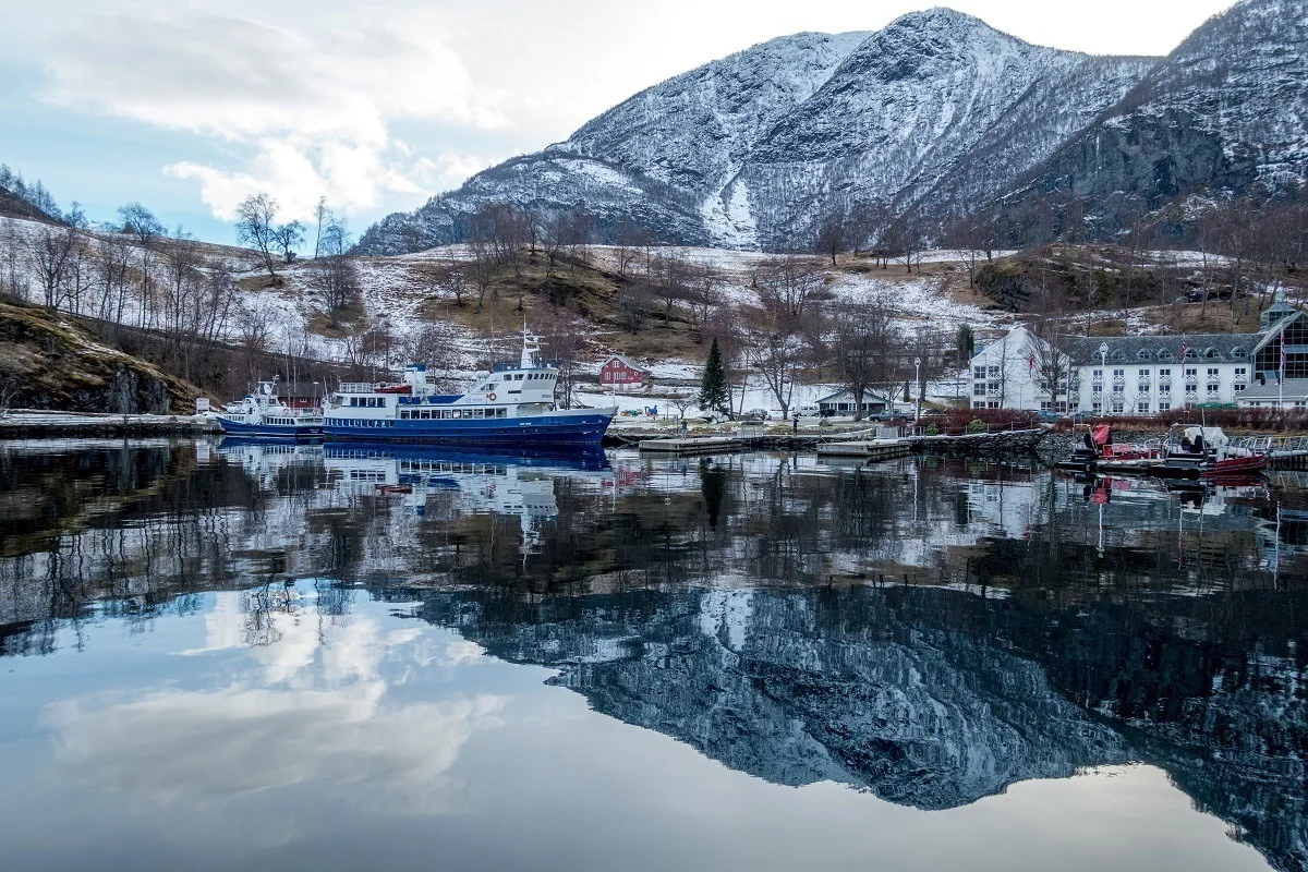 A boat in the harbor in Flam with a reflection of a mountain in the water