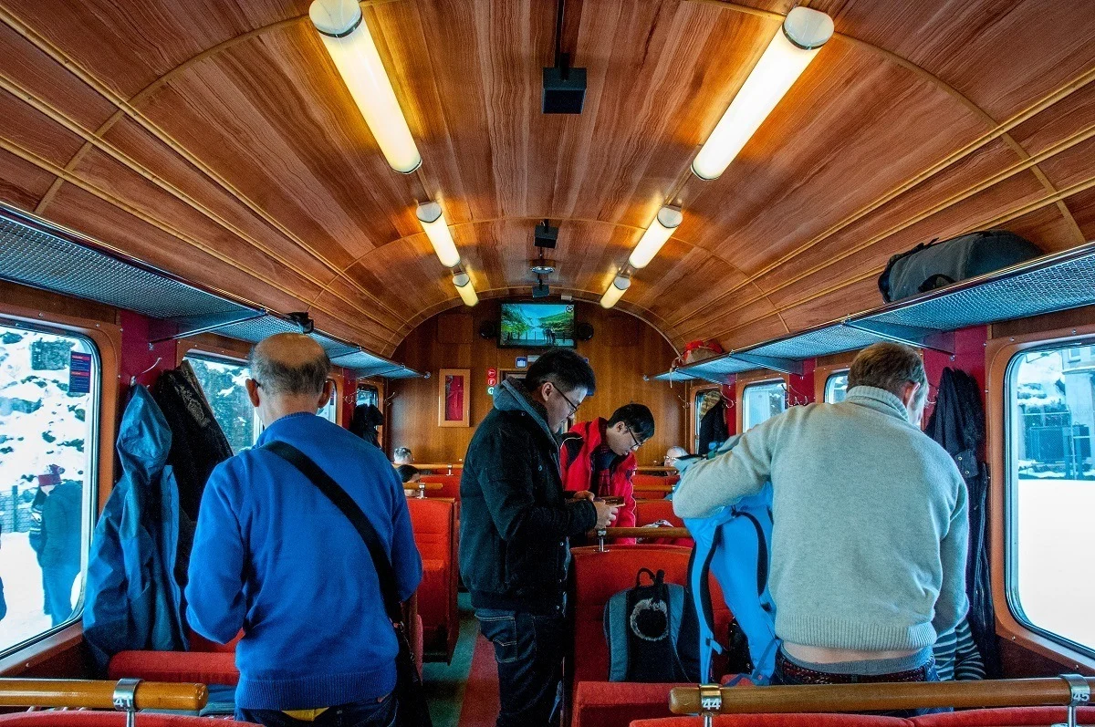 People boarding a railway car with a wooden ceiling.