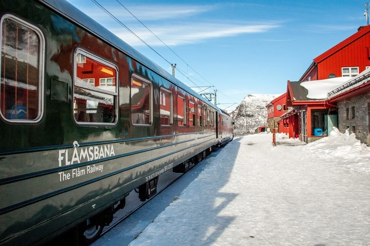 Green railway train car labeled "Flamsbana" in the snow.