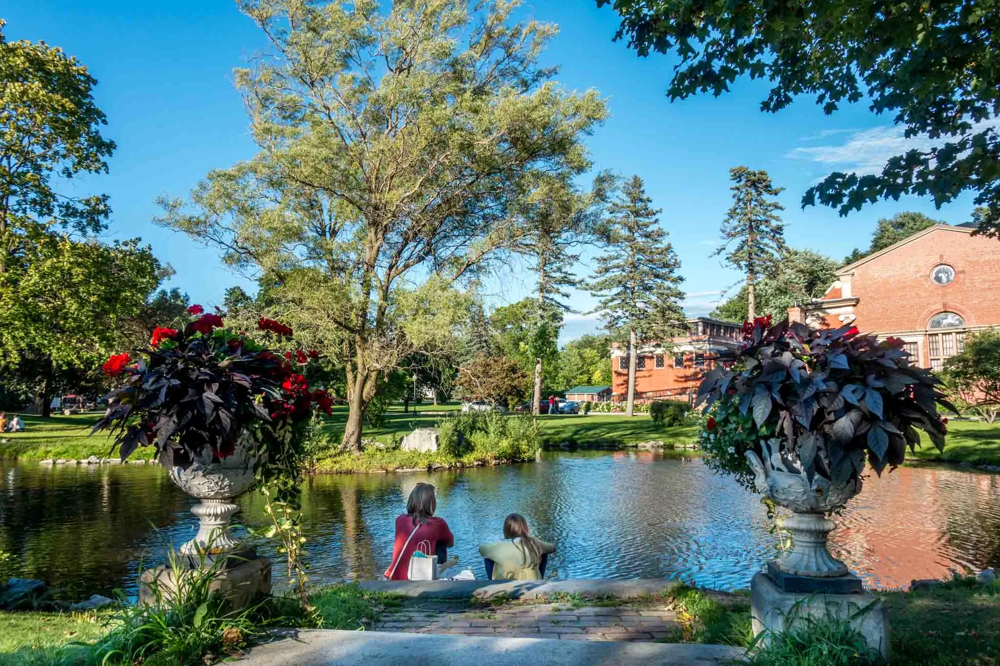 Two people sitting beside a lake in Congress Park in Saratoga Springs, New York