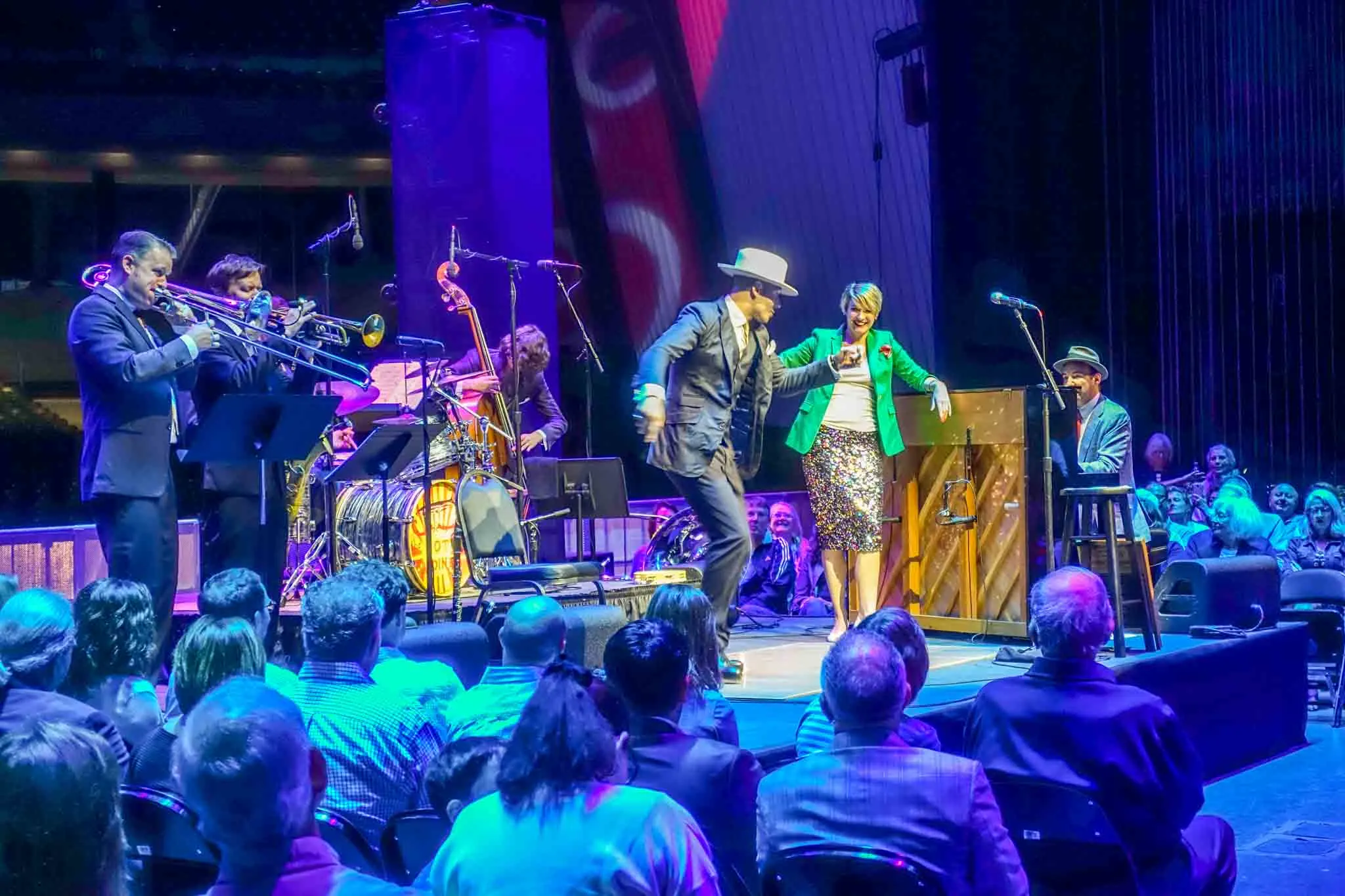 People dancing on stage with a band. 