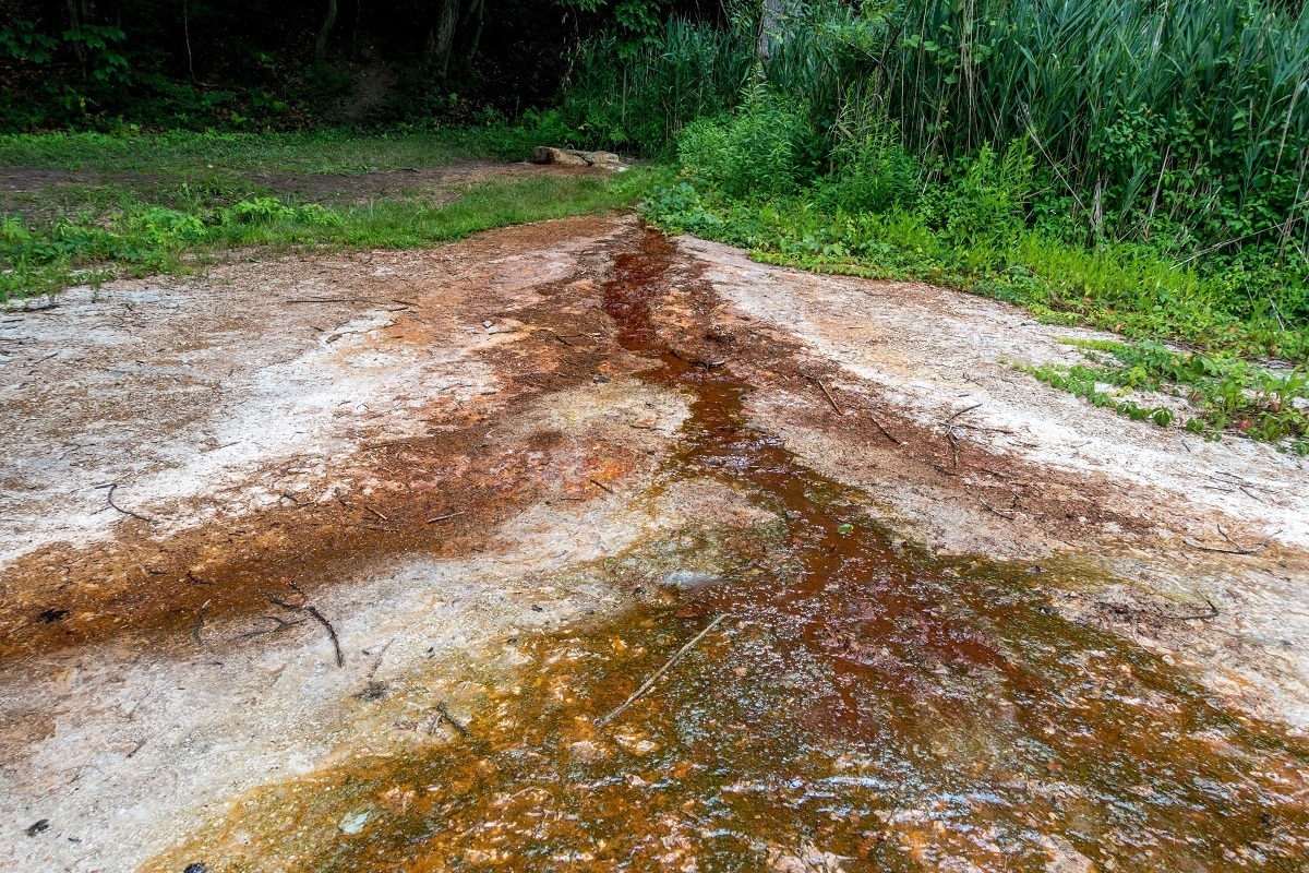 Water trickling over ground leaving dark mineral deposits