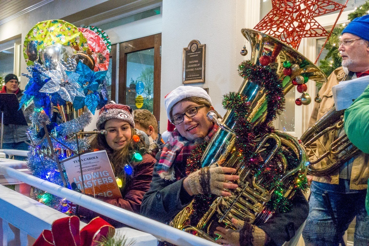 People playing tubas decorated with tinsel and Christmas lights.