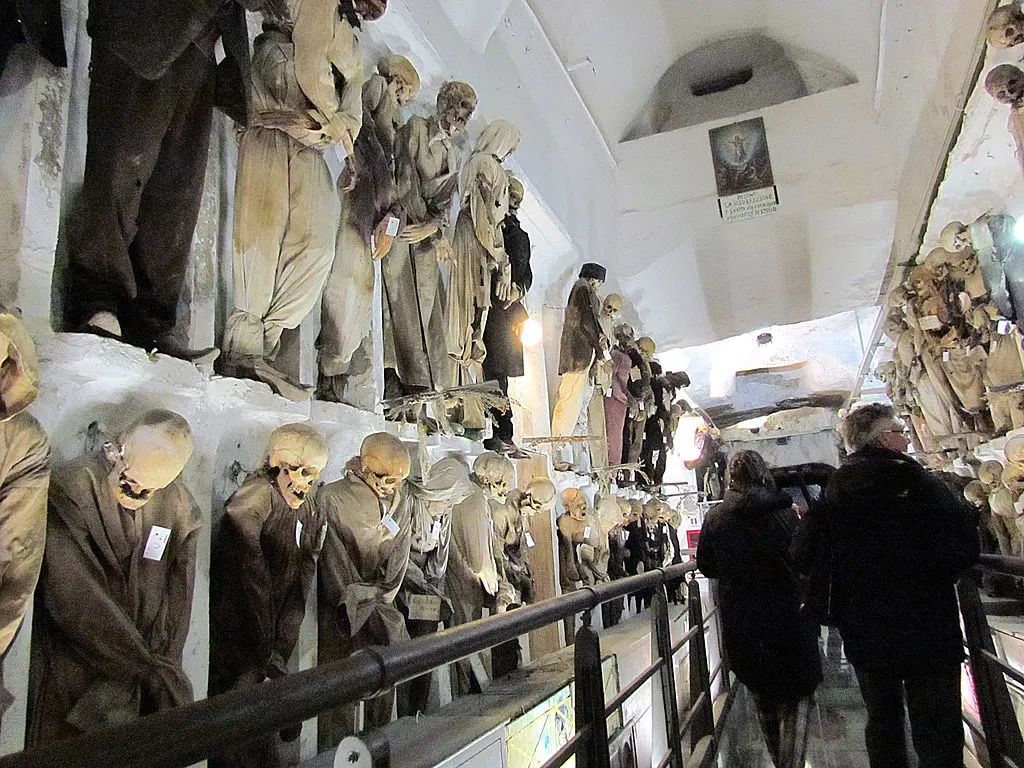 Skeletons and mummies line the walls of catacombs. 