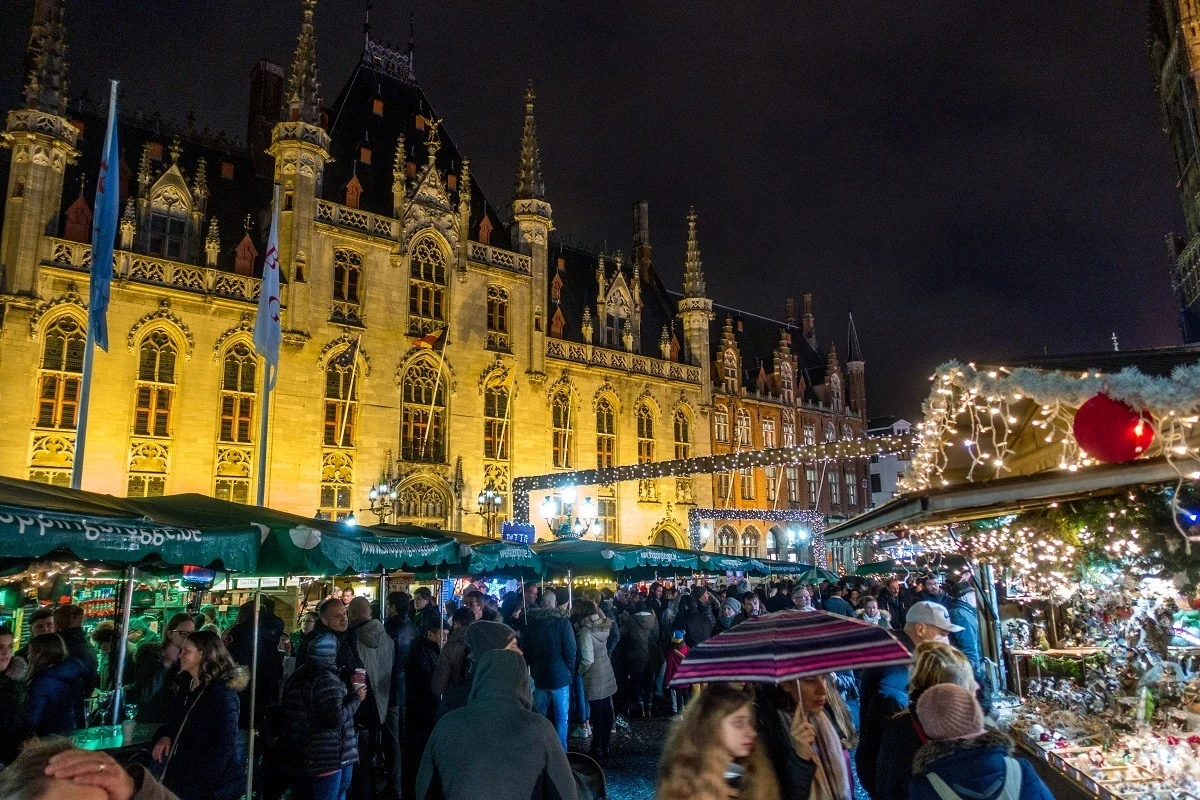 People shopping at stalls at night with buildings in the background