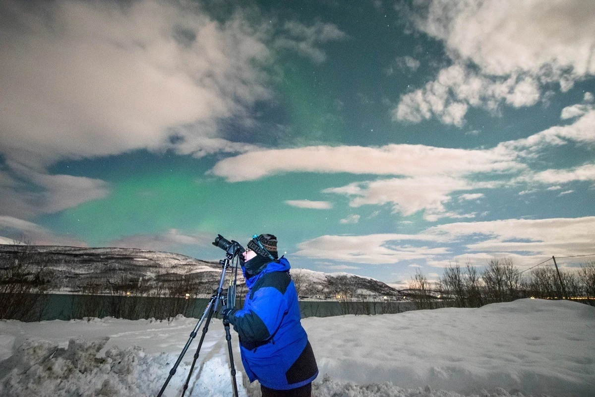 Lance looking into his camera while photographing the northern lights in Tromso
