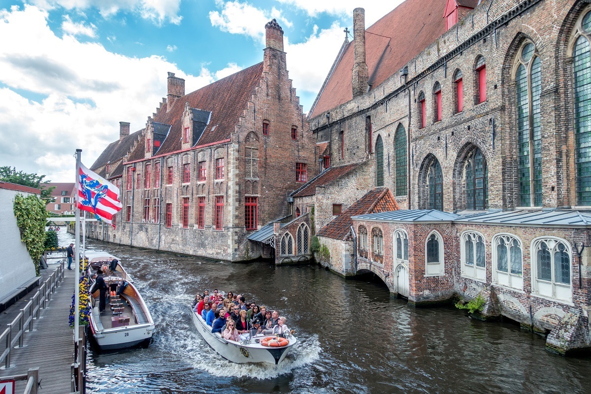 Boat full of people cruising in a canal beside historic buildings