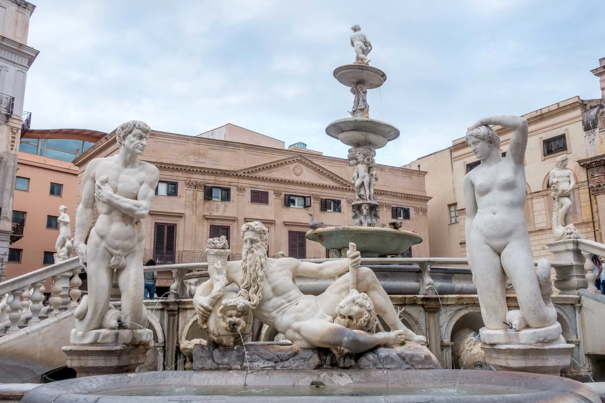 Nude human figures made of marble decorating a fountain.