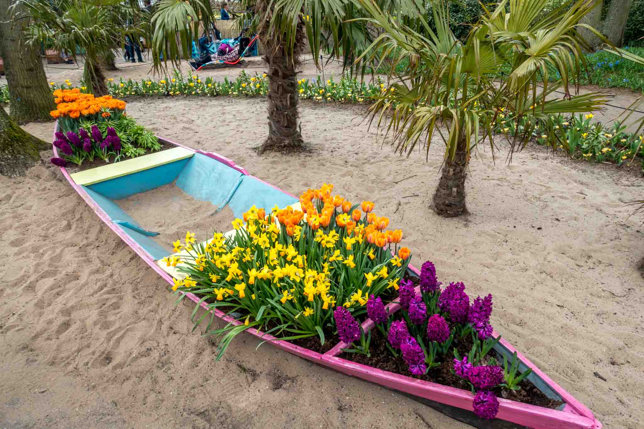 Canoe filled with flowers surrounded by palm trees