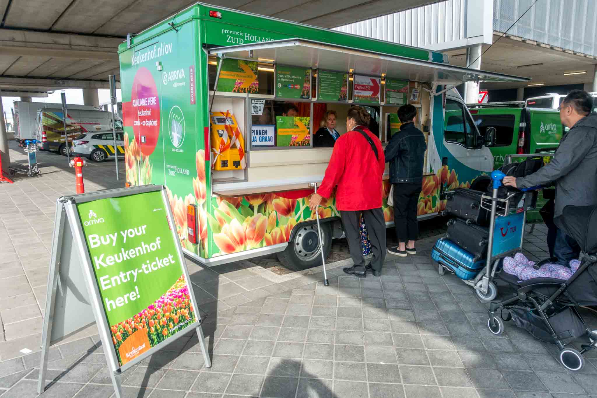People buying bus tickets at a truck beside a sign: "Buy your Keukenhof entry ticket here"