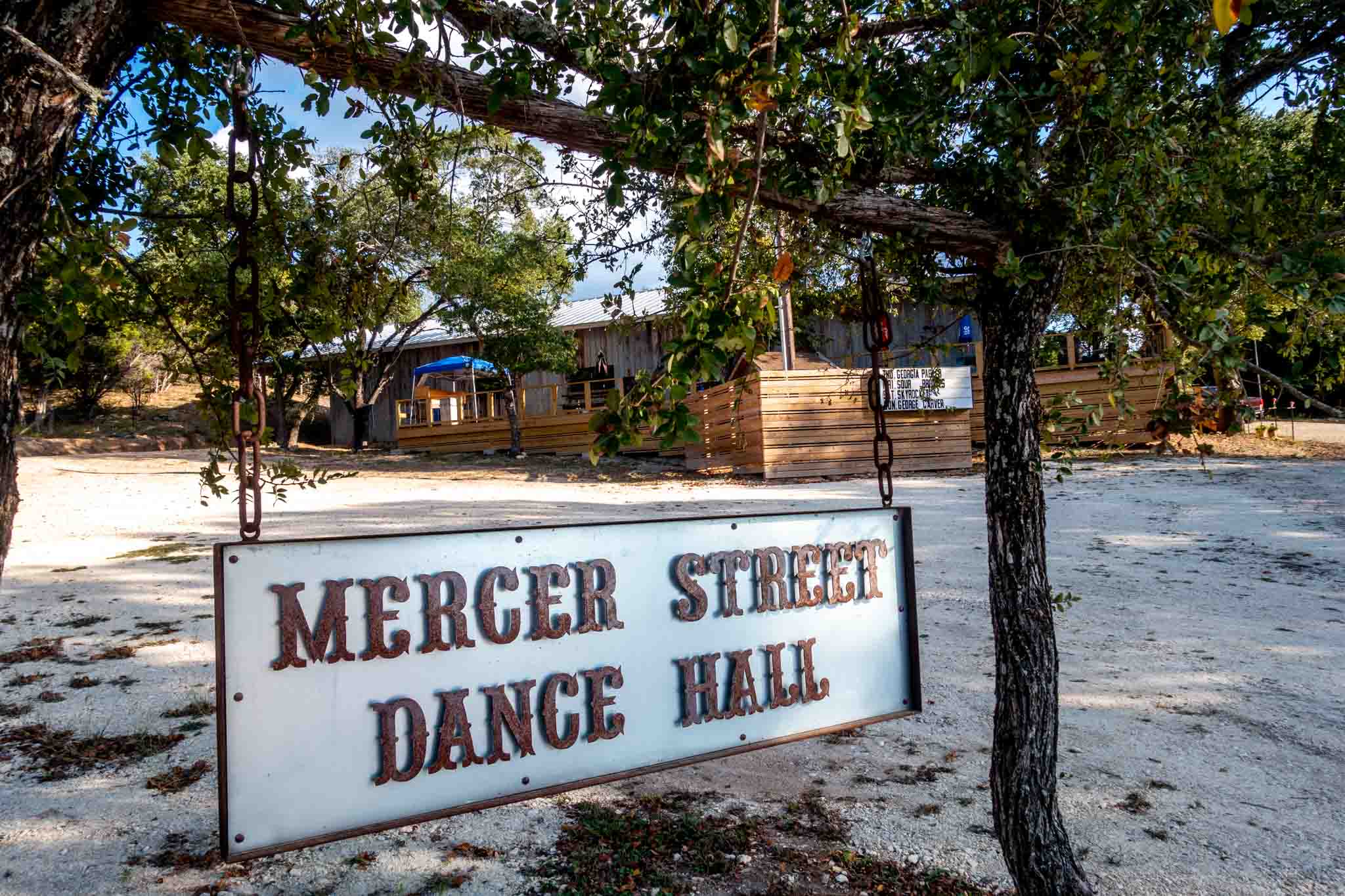 White and brown sign for Mercer Street Dance Hall hanging from a wooden post