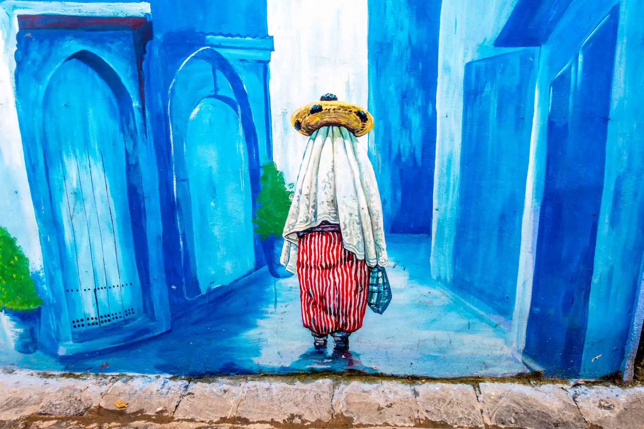 Mural of a fully-covered woman standing on a blue street