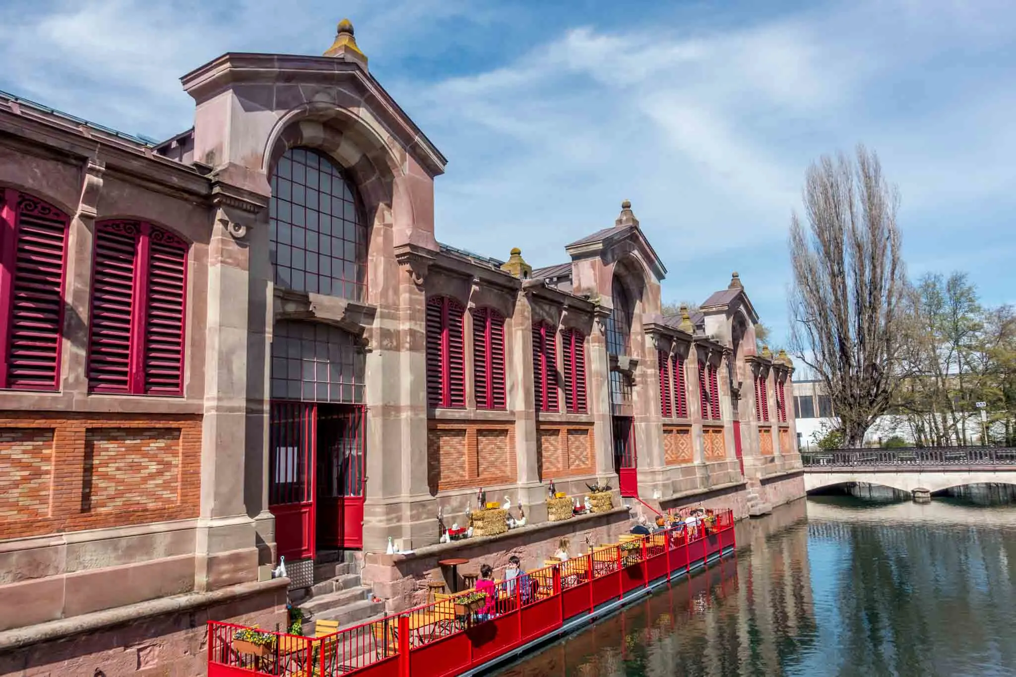 People eating on floating platform in the river alongside a building.