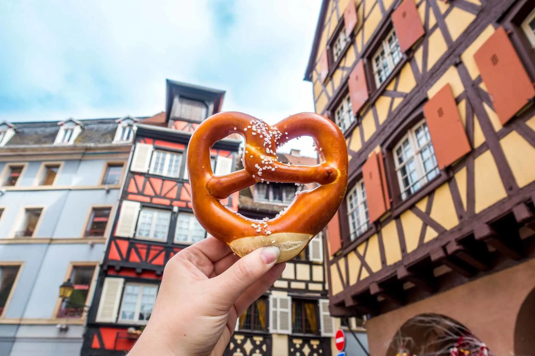 Pretzel in front of traditional Alsace buildings.