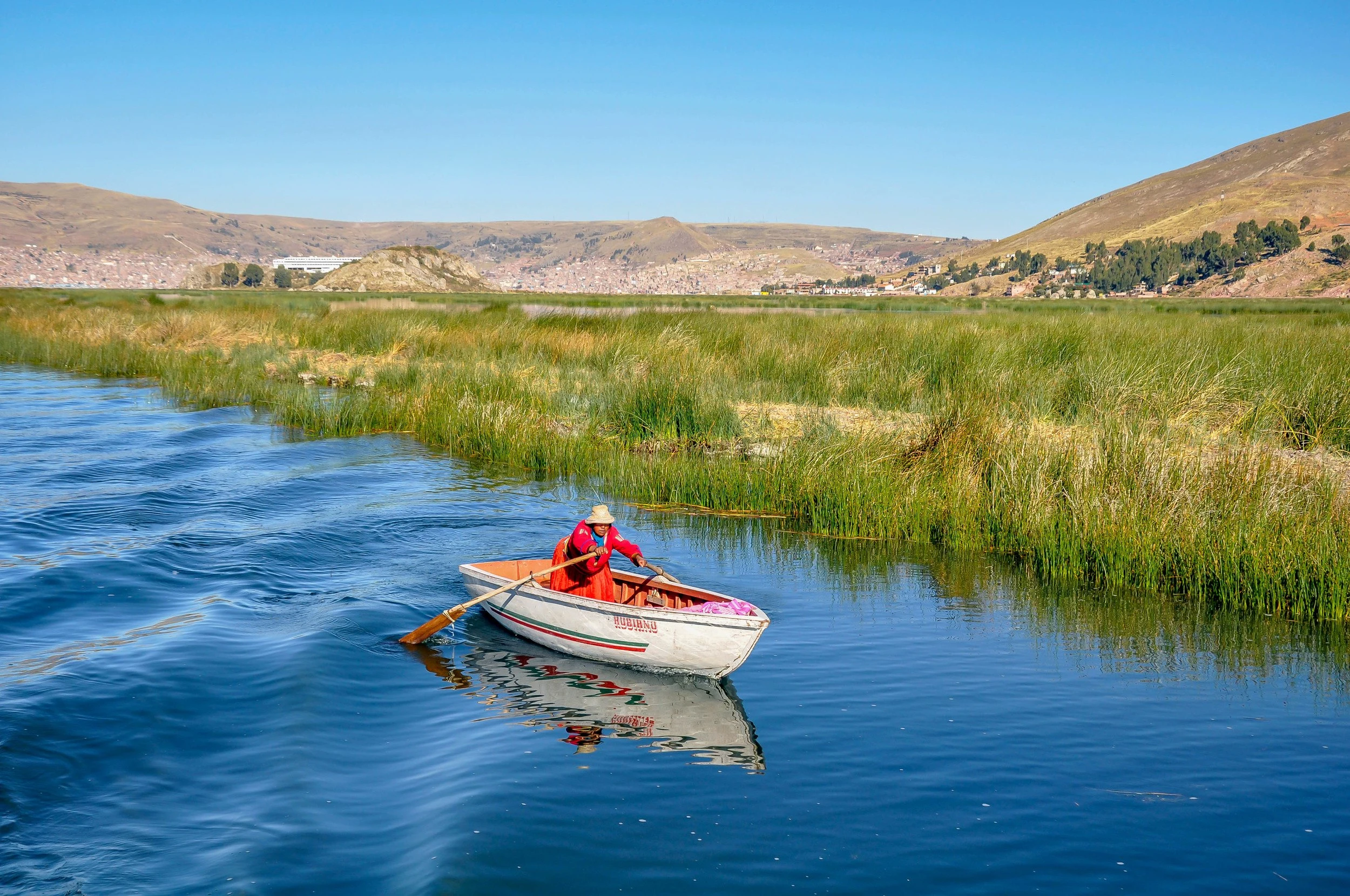 Woman in red dress rowing a boat in a lake