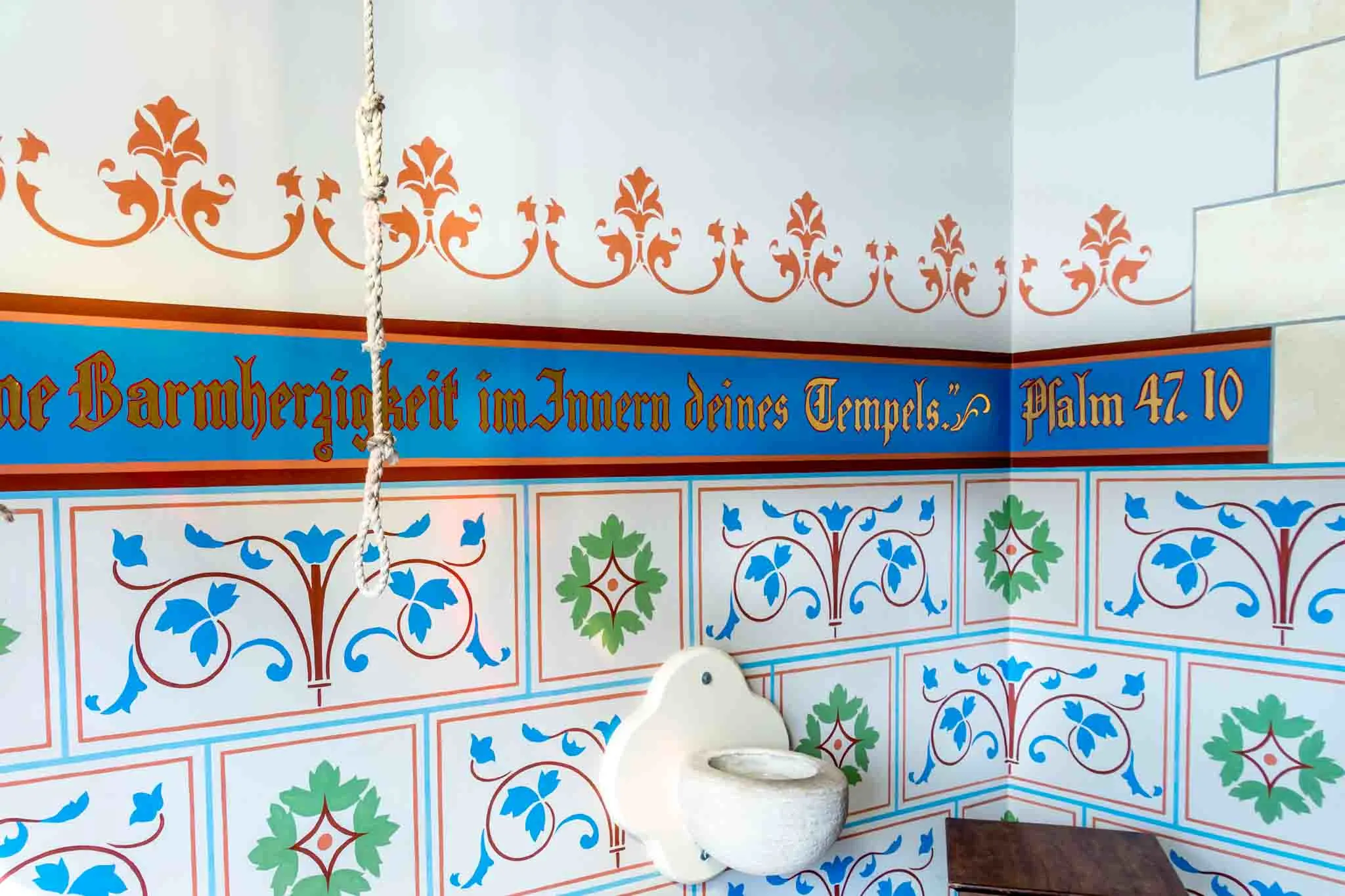 German Bible verse painted on a wall with holy water font