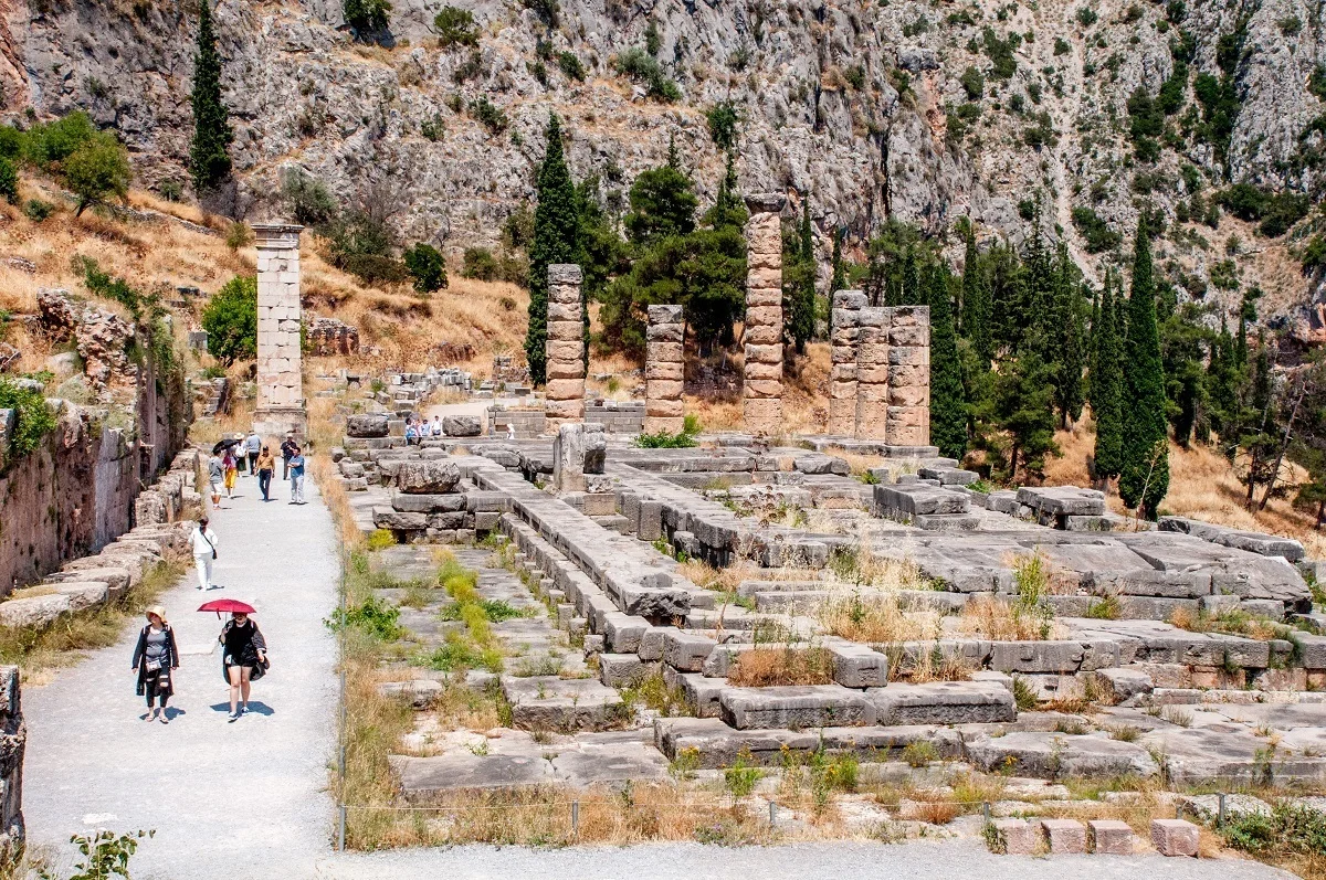 People walking by the Delphi Temple of Apollo in the hot weather