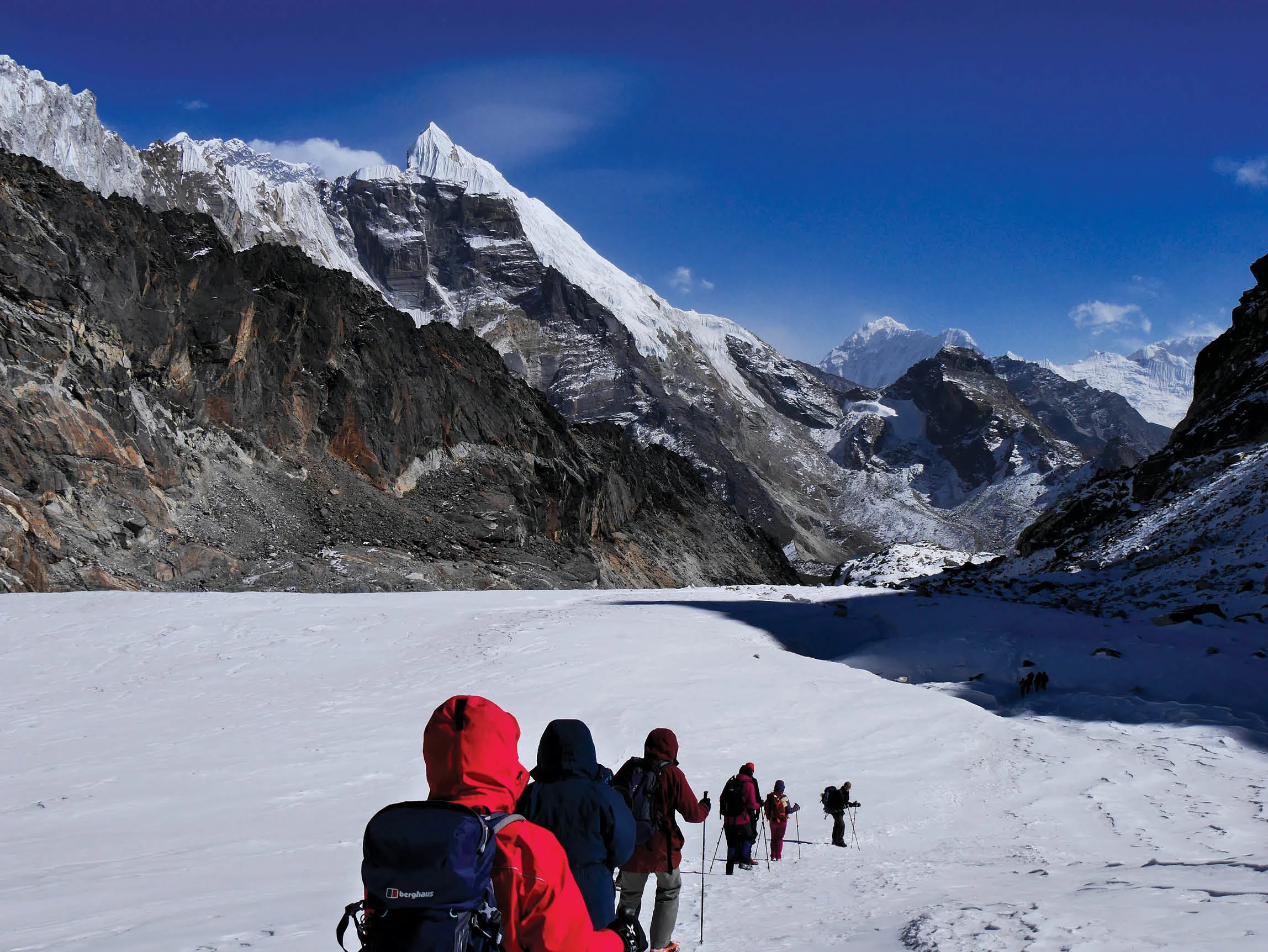 People trekking in Nepal across an ice field.