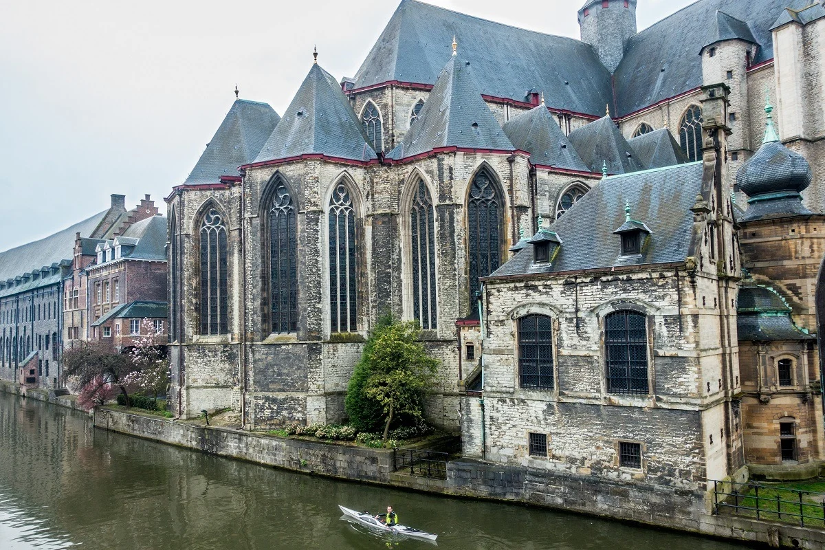 Man kayaking in a canal beside a church.