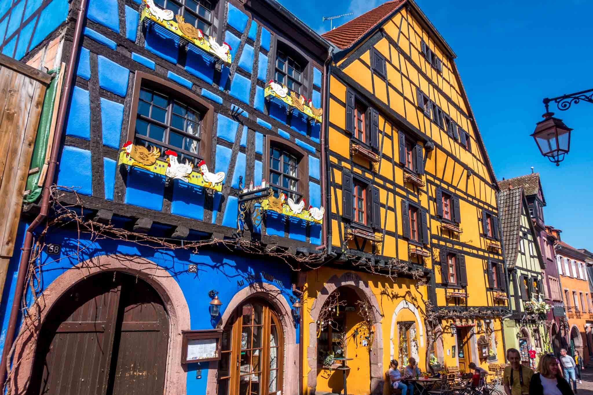 Blue and yellow half-timbered buildings line the streets in Riquewihr, France