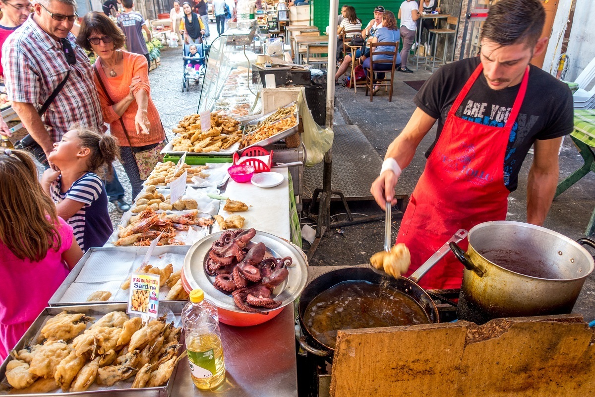 Vendor cooking seafood at an outdoor food market